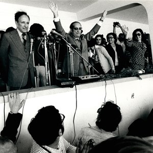 Comemorações do Dia do Trabalhador. O Presidente da República Francisco da Costa Gomes, ao centro, saudando os participantes, com o primeiro-ministro Vasco Gonçalves, à esquerda, e Maria Estela Costa Gomes, à direita.
